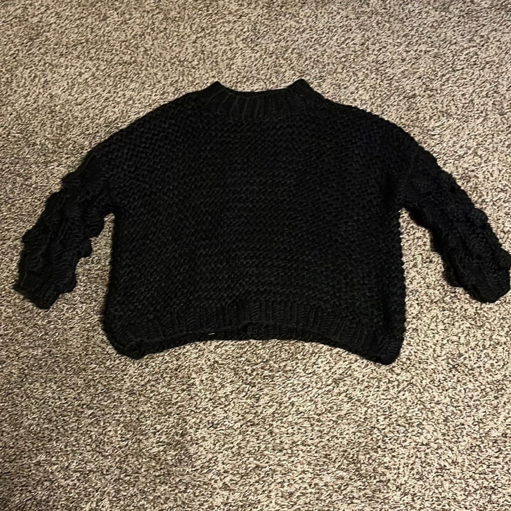 Beautiful black knitted sweater with balls on the sleeves. Never been worn.